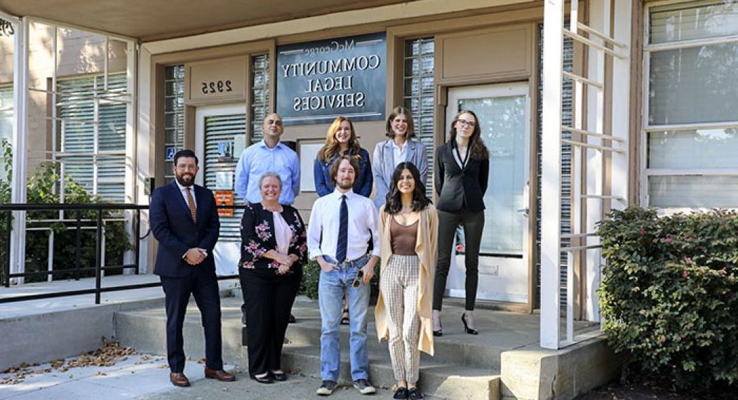 Eight people stand in front of the Community Legal Services building.