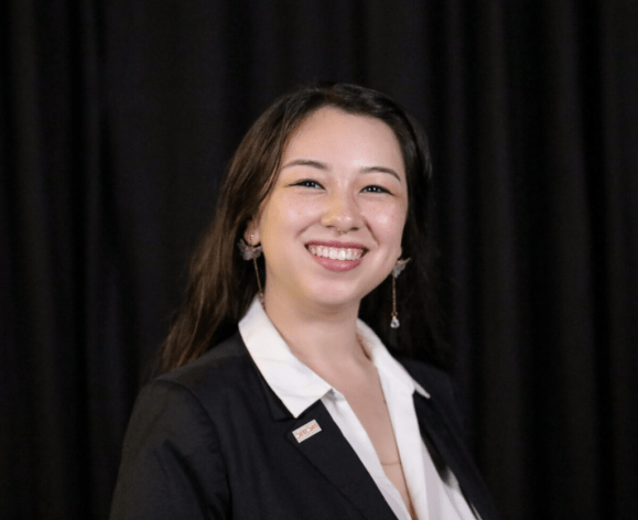 A portrait of a woman wearing a suit in front of a black background